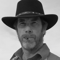 Master Dana Abbott, shown in a western hat, grins with a cigar between his lips.